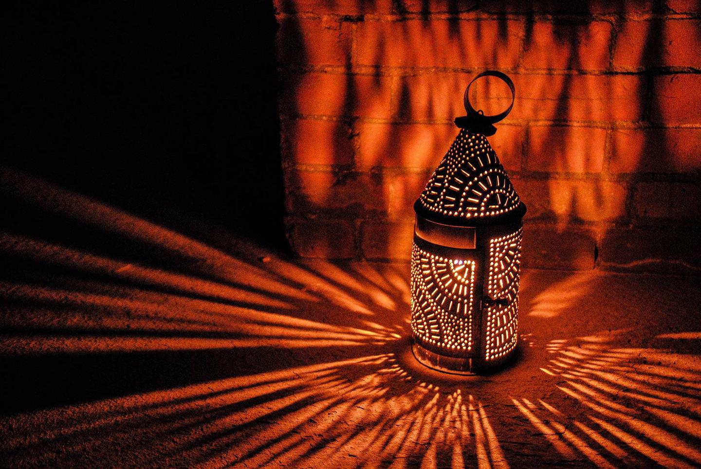 An illuminated lantern sits on the fort floorAn illuminated lantern sits on the fort floor. The metal lantern has many details which cast lace like imagery of light on the brick walls and granite floor.