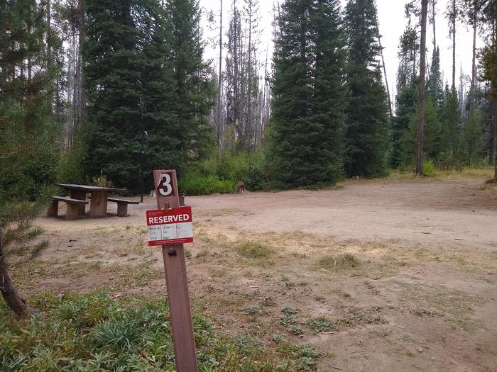 The sign for Site 3 at Edna Creek in the foreground, with parking and camping areas in the background.