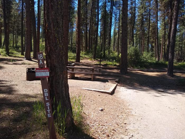A campsite in the woods, with a numbered sign in the foreground and a camp area in the background.Grayback Gulch Site 18A (a double site, paired with 18B.)