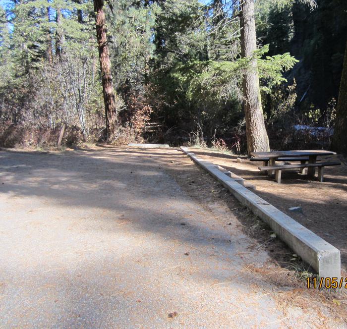 A paved driveway with a parking beam and campsite to the right.Ten Mile Site 2 parking space.