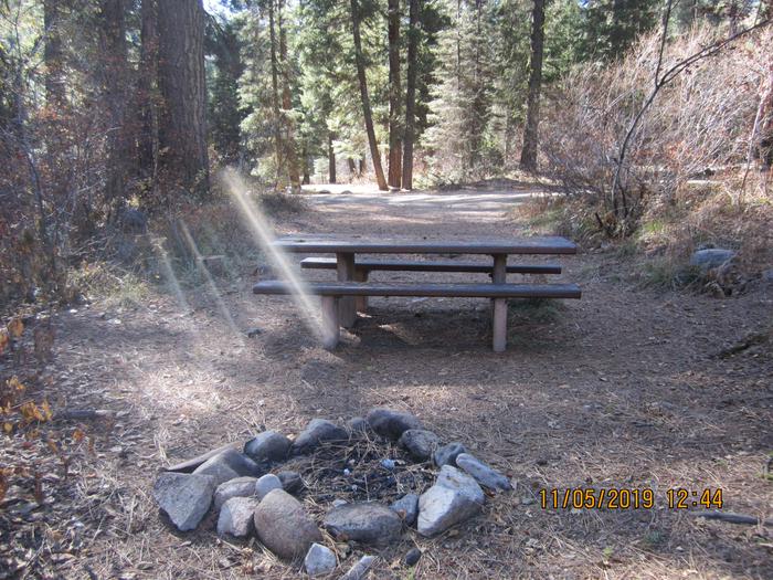 A rock fire ring and picnic table at a woodland campsite.Ten Mile Site 4.  Currently, Ten Mile Site 4 has a rock ring.