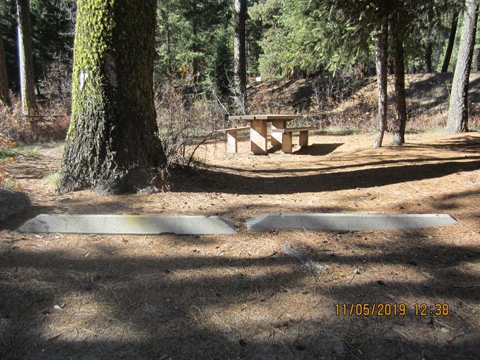 A campsite in the woods, beyond two parking beams.Ten Mile Site 8.  Note this photo was taken in November, when the campground is closed and gated.