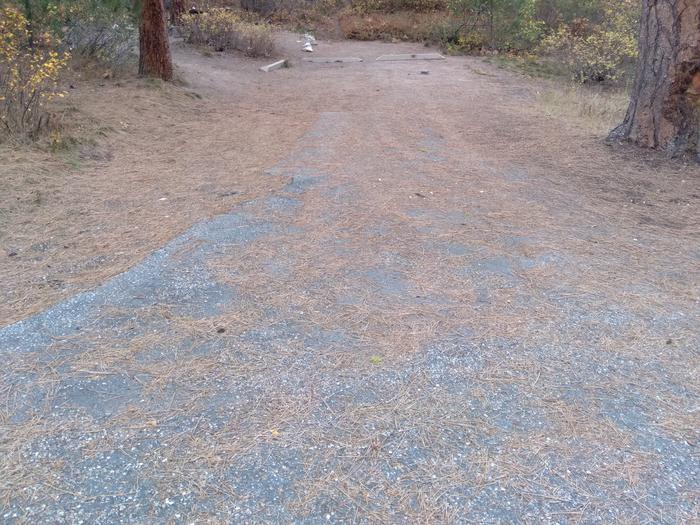 A long paved parking area in the woods, with two parking beams.Ten Mile Site 11 parking spot (campsite not shown here).