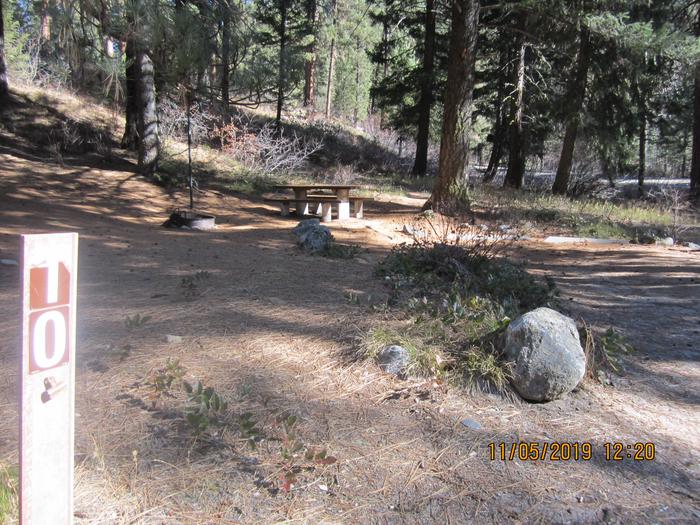 A campsite in the woods, with a picnic table and fire ring; ID Hwy 21 is in the background.Ten Mile Site 10; note Highway 21 is in the background on the right, so some traffic noise is expected.