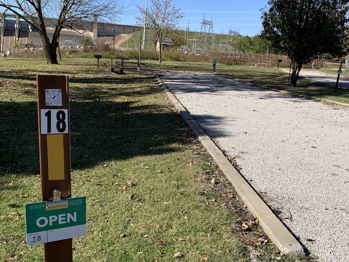 Site 18 offers a picnic table, electric hookup, water hookup, shade, lantern pole, fire ring, grill, and a tent pad.