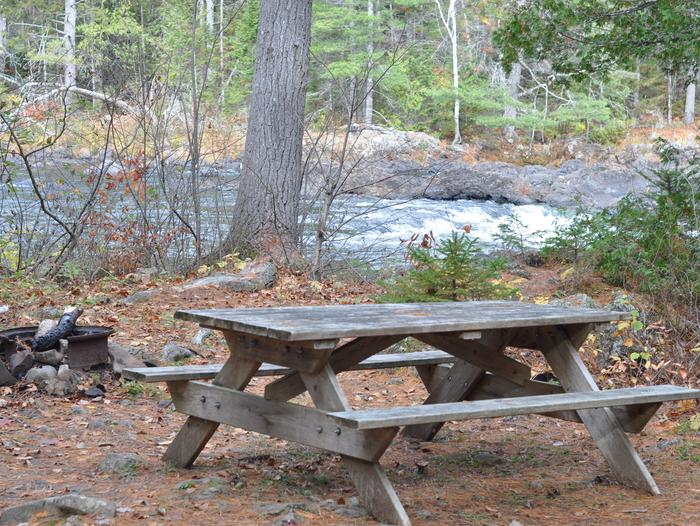 Picnic table and firepit at Pond Pitch Campsite.Located on the East Branch Penobscot River, Pond Pitch Campsite can be reached by foot or boat.