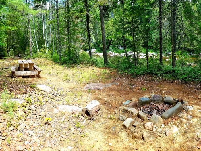 Wooden picnic table and stone fire ring at Esker Campsite along Wassataquoik Stream.Located along Wassataquoik Stream, Esker Campsite is reached by a 2-mile hike or bike on a former logging road.