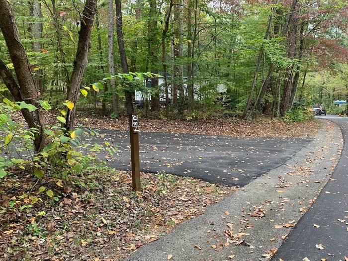 A blacktop surface with brown leaves on the sides with a small brown post.