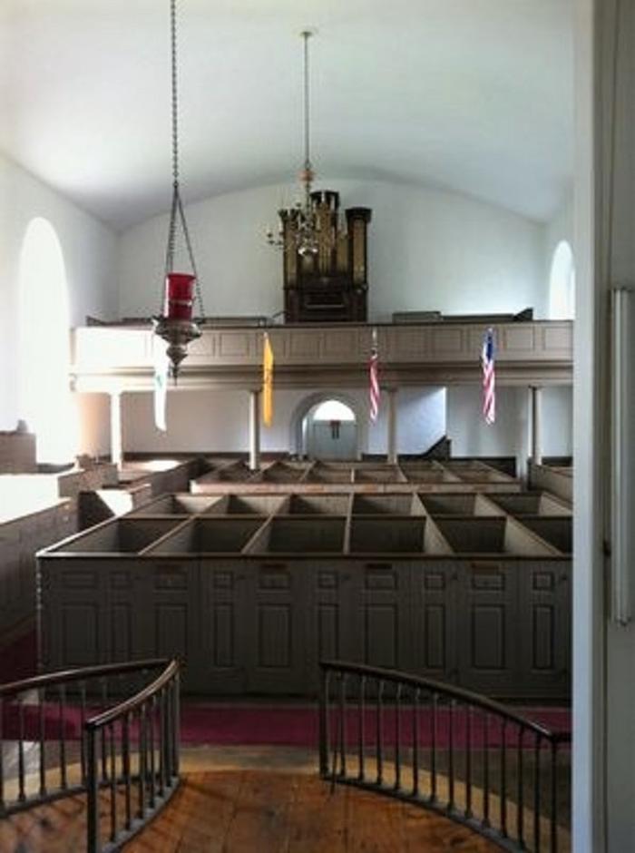 Tall church pews, with balcony and organ, flags, chandelier and sanctuary lamp. Interior of historic St. Paul's Church, showing restored 18th century box pews, gallery and 1830 Erben pipe organ, scene of the self guided tours.  