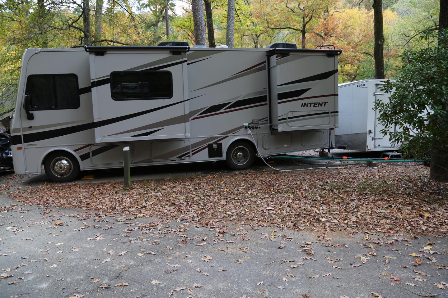 Large RV with pop out sides in campsite with fallen leaves surroundingCampsite 8