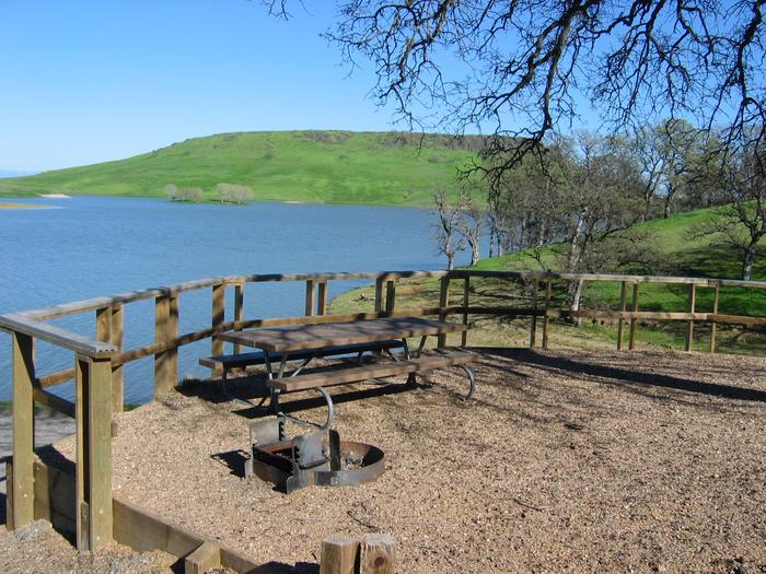 Campsite within Buckhorn Campground showing picnic table, firepit, and lake in background.Buckhorn Campsite