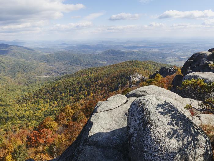 A rock cliff in the foreground of a view overlooking fall colors and rolling mountains.You could be here!