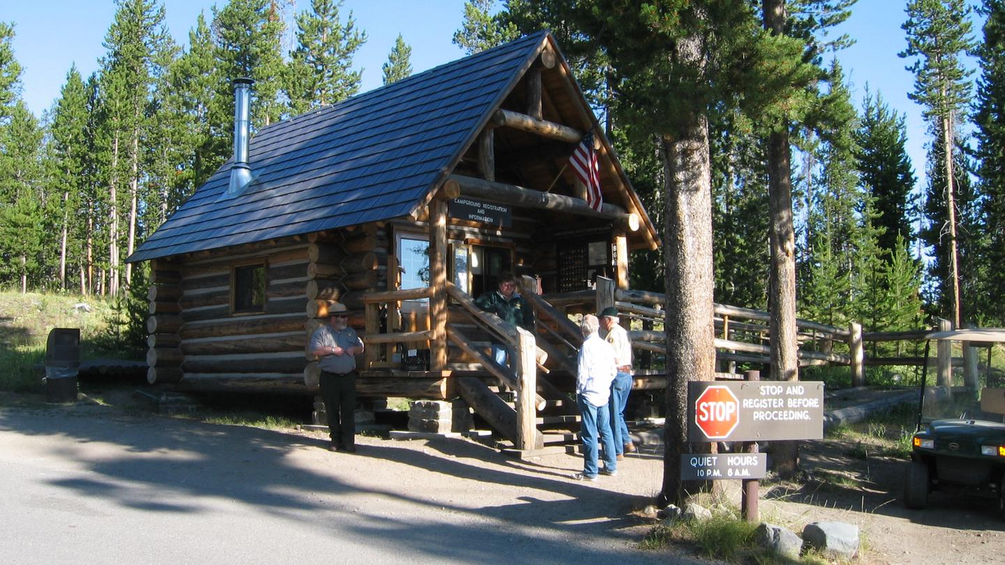 Log cabin with people and golf cart.Indian Creek Campground office with Ranger and Campground Hosts.