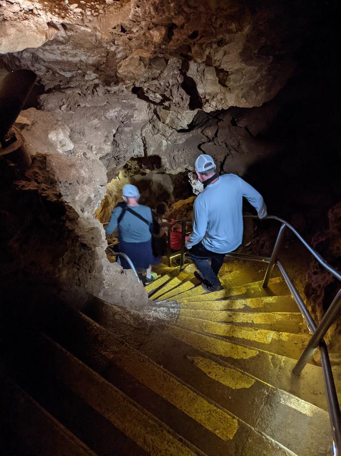 Two people descend steep stairs in a cave.Steep stairs and narrow passages are common throughout Wind Cave.