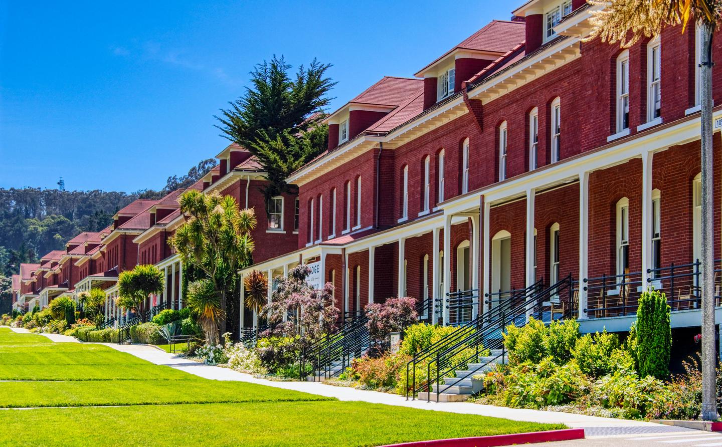 Red brick buildings with lawn.The historic Montgomery Street barracks are at the heart of the Presidio's Main Post area. These buildings now how various businesses, including multiple hotels and a boutique lodge. 