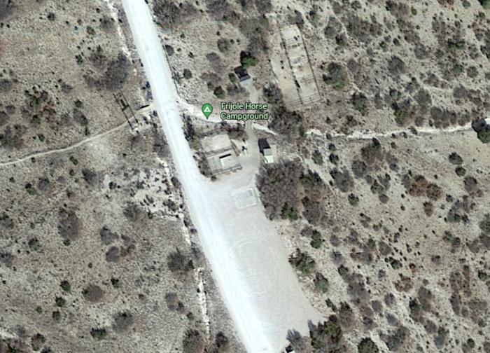 The satellite view of the Frijole Horse Corral Campground with the 2 tent pads are in the center, the corrals are to the east and a large gravel parking area to the south.This is a satellite view of the Frijole Horse Corral Campground.  It shows a large gravel area available for parking horse trailers, two tent pads and restroom.  The corrals are at the northeast corner of the campsite.