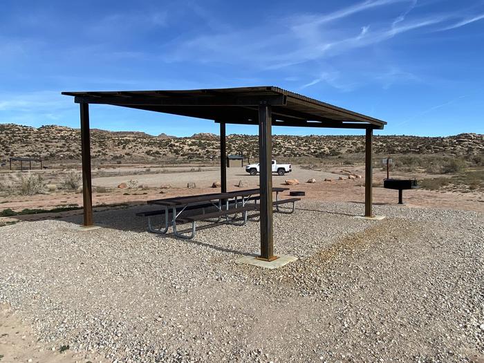 Campsite shade structure with grill, fire pit, and Group Campsite A sign.  Parking area in background.Campsite shade structure with grill and fire pit.  