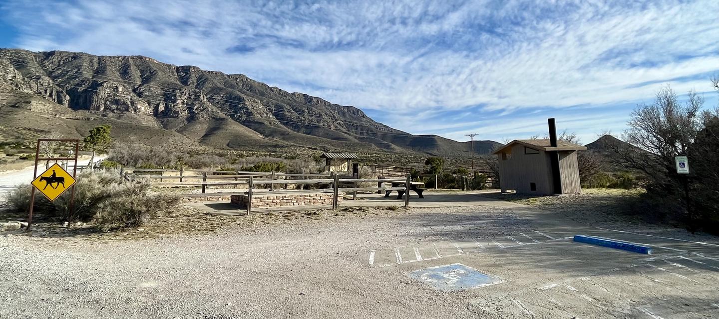Overview of Frijole Horse Corral Campsite with RV Parking in foreground, tent pads, picnic table and restroom in center and mountain views behind.Overview of Frijole Horse Corral Campsite.