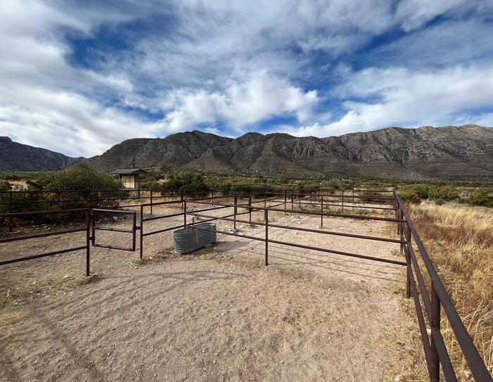 Frijole horse corral area with 4 separate corrals separated by metal rails and gate. The Guadalupe Mountains area visible in the background.Frijole horse corral area with 4 separate corrals, with the Guadalupe Mountains visible in the background.