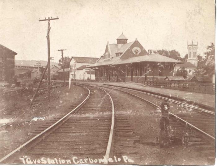 Grayscale historic photo of Carbondale stationThe Delaware and Hudson Seventh Avenue train station opened on February 1, 1896. The station was widely regarded as one of the finest and most modern depots in the Lackawanna Valley. Local and express trains, both north and south, from Carbondale arrived and departed from Carbondale on a daily basis. In the 1950s, as many as fifteen passenger trains departed daily from this station for Scranton.