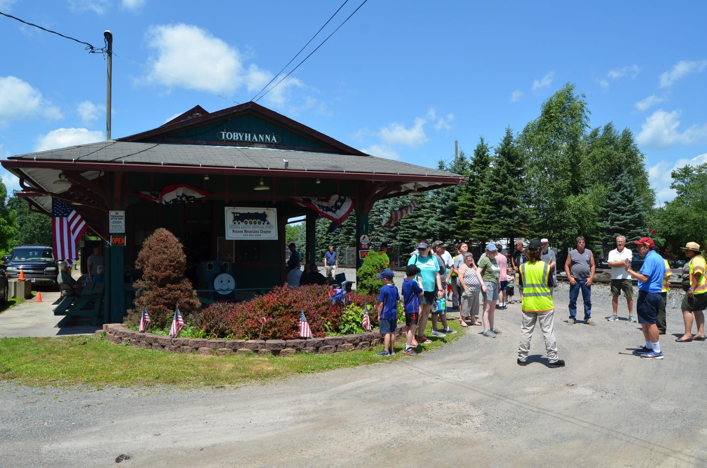 A crowd of approximately 15 people gathered outside at Tobyhanna StationMembers of the Coolbaugh Township Historical Association provide optional walking tours of the Town of Tobyhanna. The tour includes a look at the historic past of Tobyhanna that was originally the hub of the logging industry thanks to the easy access to the Railroad.