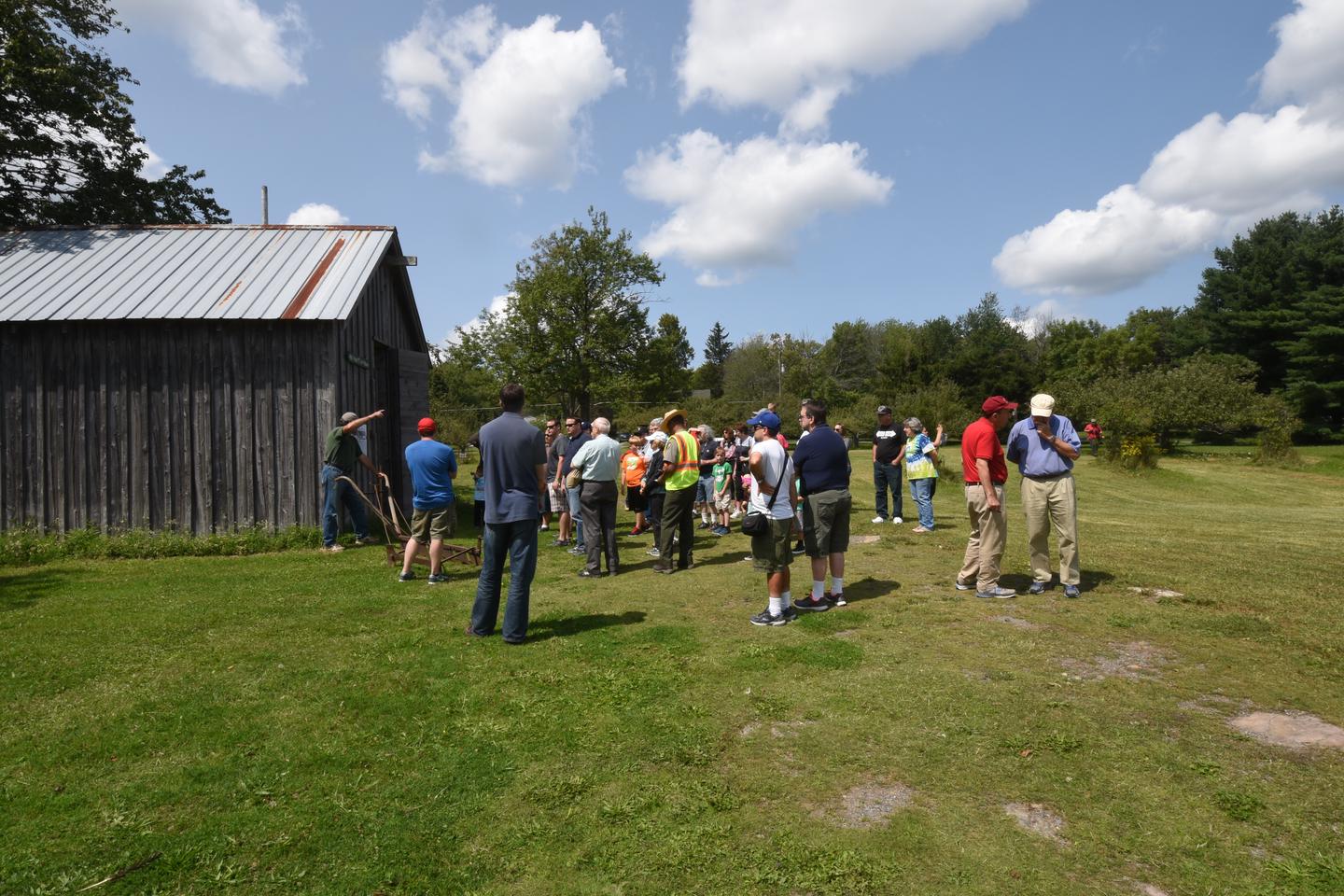 A crowd of approximately 30 people gathered outdoors in front of historic ice houseMembers of the Coolbaugh Township Historical Association provide an optional walking tour of the Tobyhanna Millpond #1 Ice House where an ice harvest is held each year. It is about a ½ mile walk to see historic ice harvesting tools and ice that was harvested in January