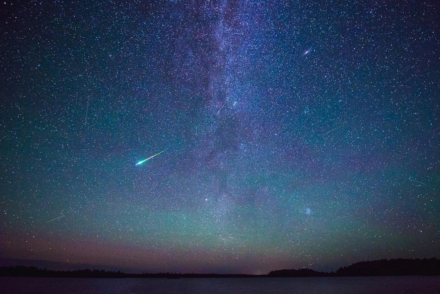 The Perseid meteor shower and Milky Way galaxy against a dark starry sky at Voyageurs