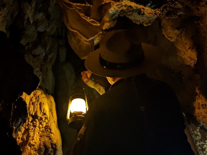 Ranger holding lantern while moving through Middle Cave Fault LineCentennial Lantern Tour