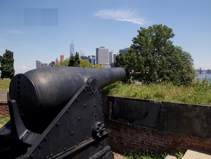 Large, black, iron cannon, pointing over the north wall of Fort Jay, NYC skyline in the backgroundThe cannons of Fort Jay silently watch over NY Harbor