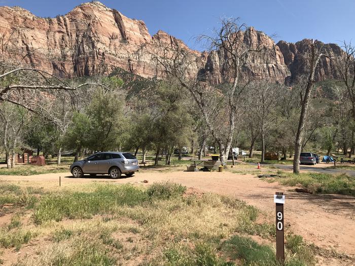 Vehicle parked in campsite in front of Zion's red sandstone cliffs. South Campground Site 90