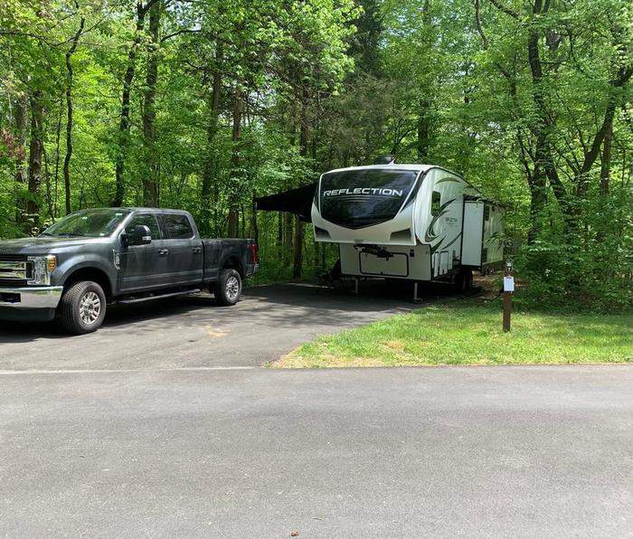 A blacktop surface with a black truck and black and white fifth wheel.