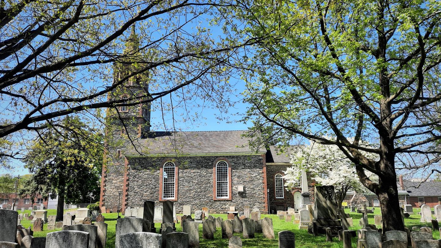 Masonry church, with steeple and a cross, and trees visible. Recent image of St. Paul's Church.  