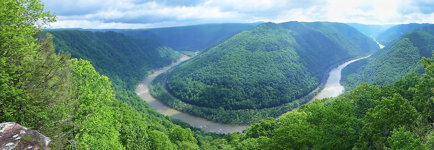 Color photo of a horseshoe bend in the river with the gorge on either side covered in green foliageMain Overlook View
