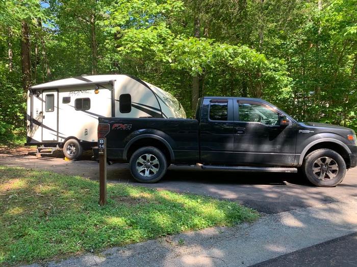 A black truck with a white and black camper.