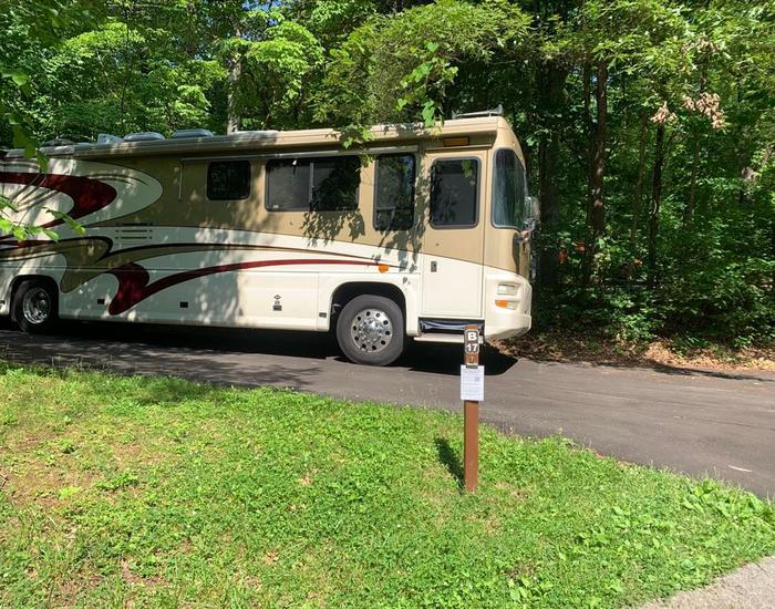 A white and tan RV on the blacktop pad.