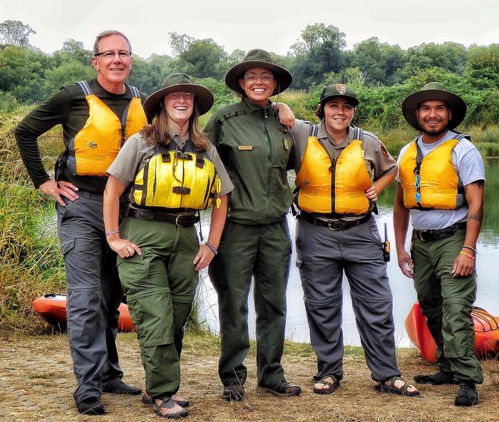 Five park rangers wearing lifejackets by the kayak launch.Kayak rangers ready for tours