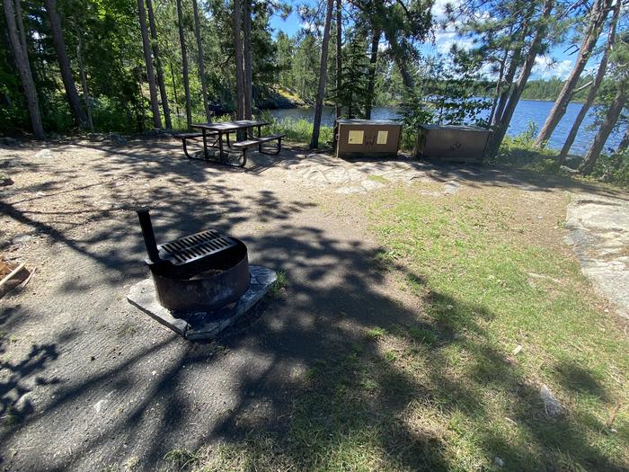 R13 - Fish Camp Island, view looking towards camp with view of a fire ring, bear box, and picnic table.View of campsite