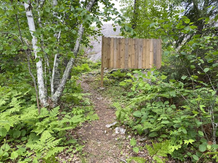 R14 - Hanson, trail to privy with a wood planked privacy guard.Privacy guard for privy
