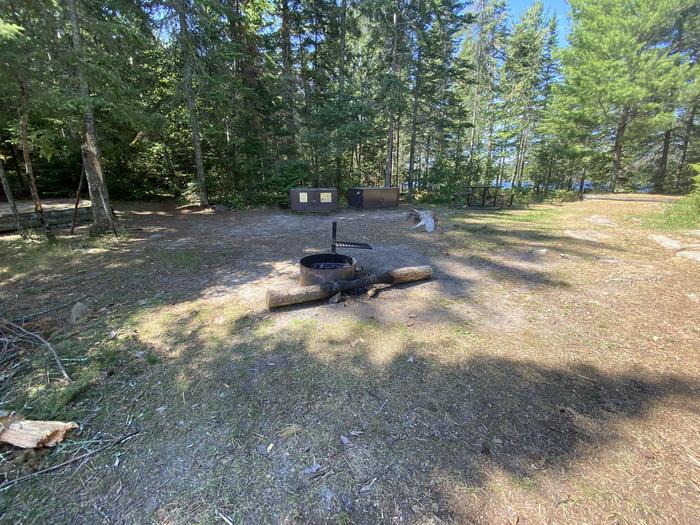 R18 - Little Finlander Island, view looking into campsite with fire ring in the foreground with tent pads, picnic table, and bear boxes in the background.R18 - Little Finlander Island campsite on Rainy Lake