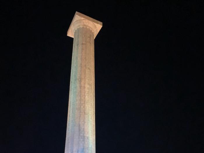 Tall stone memorial light up against a dark night sky.Memorial at night.