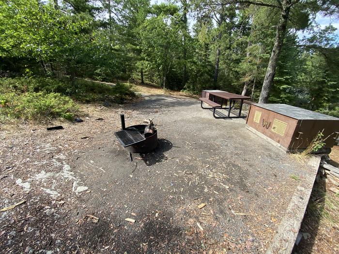 R53 - Makinen Point, view looking into campsite of the fire ring surround on one side by the bear boxes and picnic table.View of campsite