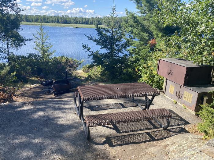 R55 - Jack Pine Bench, view of looking out from campsite with the picnic table, bear boxes, and fire ring at campsite.R55 - Jack Pine Bench campsite on Rainy Lake