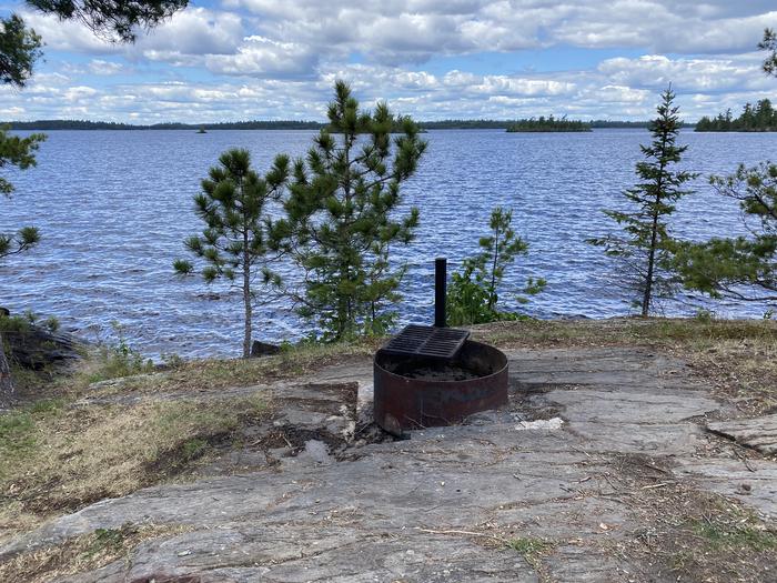 R67 - Stones Point, view looking out from campsite of the fire ring with water in the background.R67 - Stones Point campsite on Rainy Lake