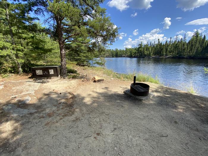 R102 - Nelson Island, view looking out from campsite with the fire ring and a bear box.R102 - Nelson Island campsite on Rainy Lake