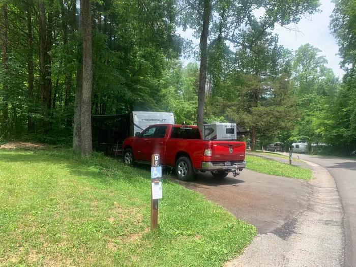 A red truck with a white camper on a blacktop surface.