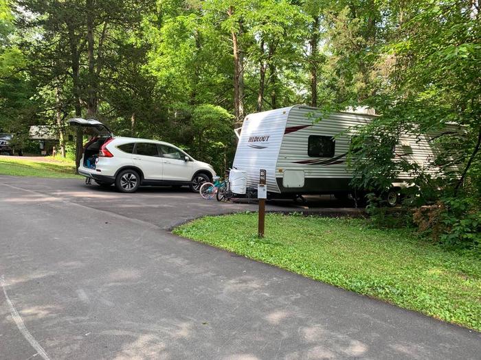 A blacktop surface with a white vehicle and camper.