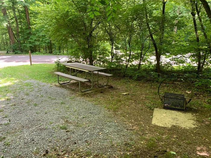 A gravel surface with a circle fire ring and brown picnic table.D-6 fire ring and picnic table area.