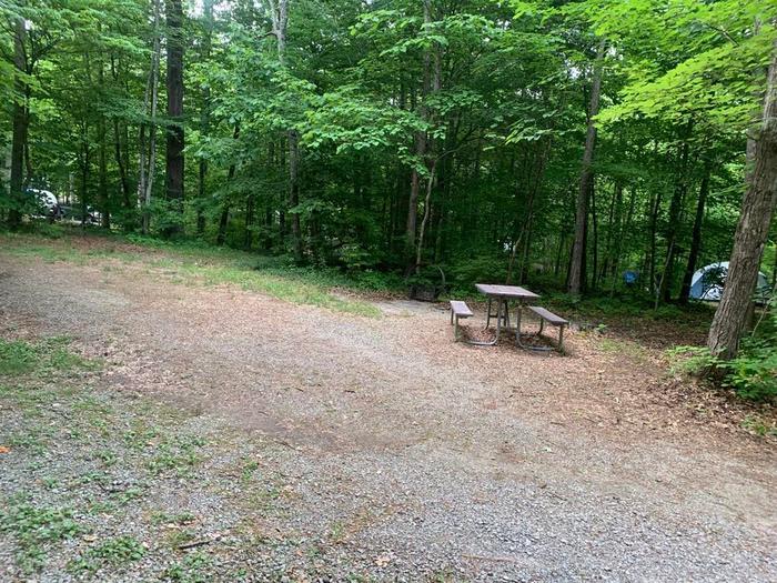 A gavel area with a brown picnic table.D-21 camping space.
