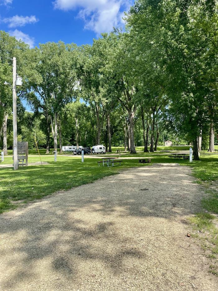 A photo of gravel driveway of Loop Upper at BLACKHAWK PARKSite 7- grass and fire pit behind site. Located close to pit vault toilet and playground.