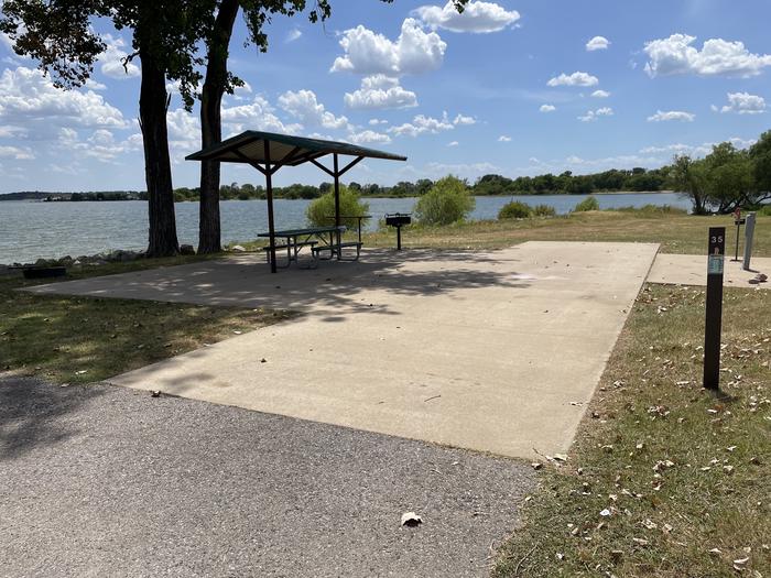 A photo of Site 035 of Loop BRUE at BURNS RUN EAST with Picnic Table, Electricity Hookup, Fire Pit, Shade, Waterfront, Water Hookup